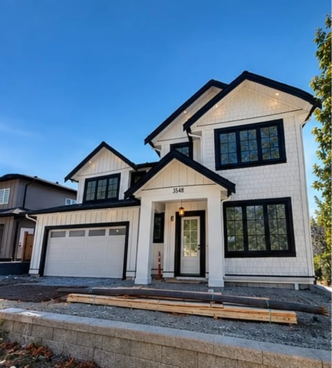 Modern two-story house with white and black exterior, garage, large windows, and landscaping on a clear day